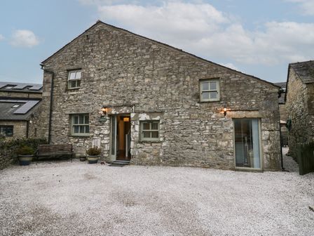 Exterior view of a stone building with windows a door a bench and potted plants at Lady Barn in Grange-Over-Sands