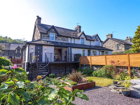 A stone and white exterior house with a balcony and garden at Dola in Pentre Du near Betws-Y-Coed