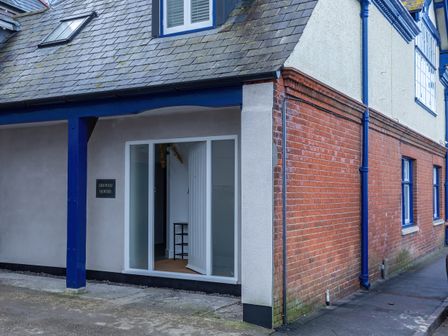 The exterior corner of a building with blue beams a glass door partially open and a sign that reads Groves House at Groves House Castletown near Fortuneswell