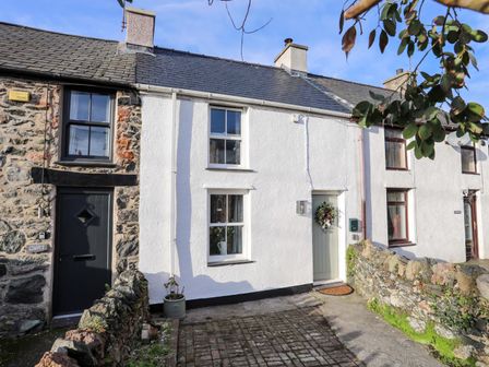 A row of stone and white painted terraced houses with front doors and windows at Cwrt in Dwyran near Niwbwrch Newborough