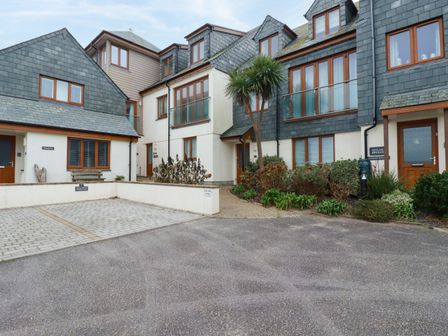 A group of townhouses with slate roofs and wooden framed windows with small garden and parking spaces at Blue Horizon in Port Isaac