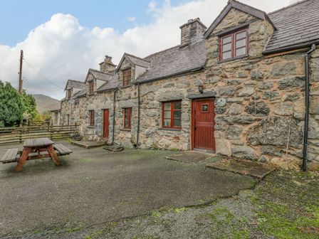 Stone cottages with brown wooden doors and windows and a picnic table outside at Ysgubor in Dinas Mawddwy near Dolgellau