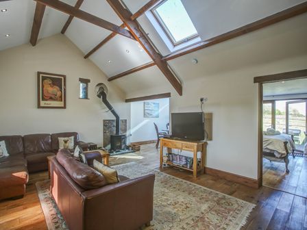 A living room with leather sofas wood stove and television at Upper Calffield Barn Camrose near Haverfordwest