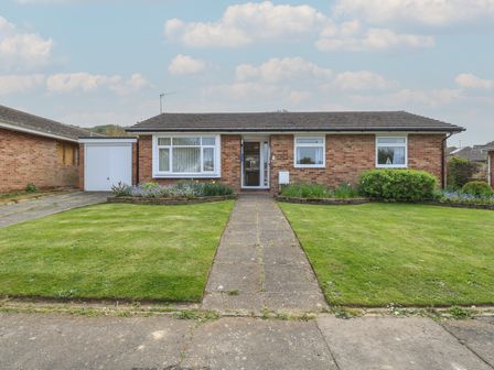 A brick bungalow with a tiled roof a front garden with a path and flower beds at White Lion Retreat in Cromer