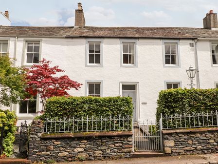 A white two-story house with a stone wall hedges and a metal gate at Middletown in Keswick