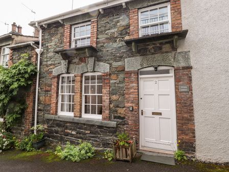A stone and brick house exterior with white windows and door at Stone Ledges in Keswick
