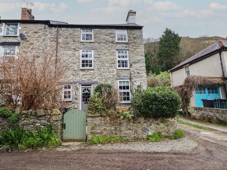 A stone cottage with a door and windows at Riverwash Cottage Dwygyfylchi