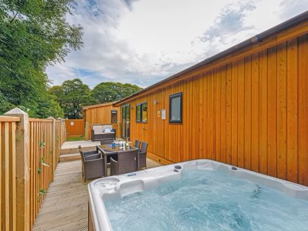 An outdoor deck with a hot tub dining table and chairs and a seating area at 6 Yeoman Hey Lodge in Greenfield