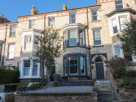 A row of brick terraced houses with bay windows and front gardens at 27 Westbourne Grove in Scarborough