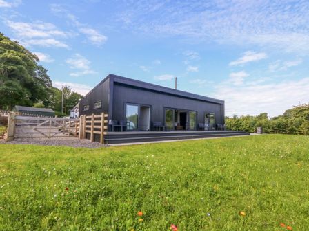 An outdoor view of a house with patio and fence at Y Cwt Moelfre