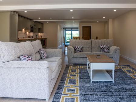 A living room with two sofas a coffee table and an open kitchen area at Bears Court Barn 7 Little Rissington near Bourton-On-The-Water