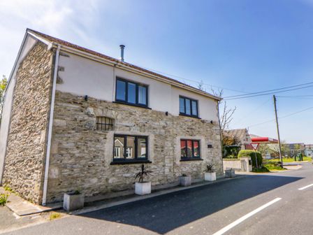 A house with stone exterior and windows on the street at La Bastille in Maenclochog