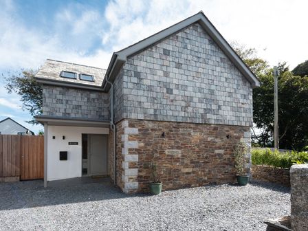 A house with stone wall and shingle roof at Pentire in St Minver
