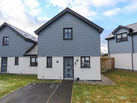Front view of a modern detached house with a driveway and grass lawn at 19 Parc Delfryn in Benllech