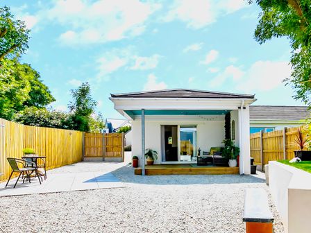 A patio with chairs table and potted plants in a fenced yard at The Studio in Crackington Haven