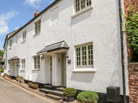A street view of white cottages with small plants outside at Little Dragons Dunster near Minehead