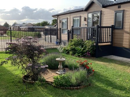 A garden with a flowerbed and decking at Longdon Lodge Wickhamford near Evesham