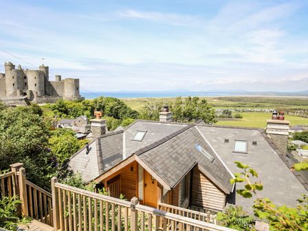 A house with a wooden porch and grey roof near a castle and open fields at Bryn Awelon in Harlech