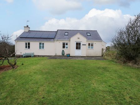 A house with solar panels on the roof a front door and green grass in the yard at Tan Y Ffordd near Tudweiliog