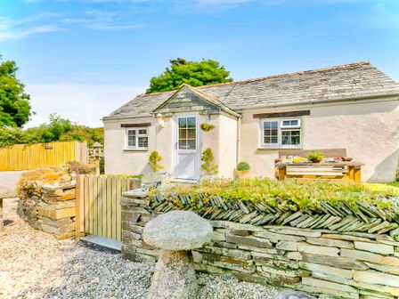 A small cottage with a wooden gate stone wall and outdoor picnic table in Crackington near Crackington Haven