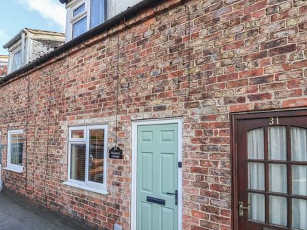 Brick exterior wall with a mint green door labeled 29 and a wooden door labeled 31 at Chestnut Cottage in Wetwang near Great Driffield
