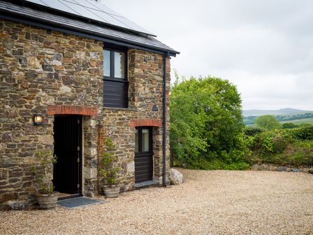 An exterior view of a stone house with a gravel area at The Red Barn near Lydford