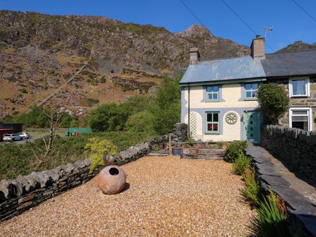 A cottage with a gravel garden and stone walls in a mountainous area at Miners Rest in Blaenau Ffestiniog