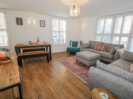 A living room with a sofa and dining area at Betty's Buoy Weymouth