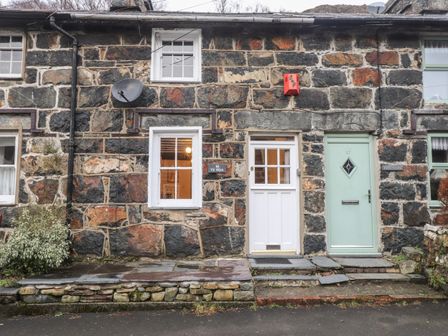 A stone house exterior with two white windows and two doors one white and one green at Ty Glyn in Beddgelert