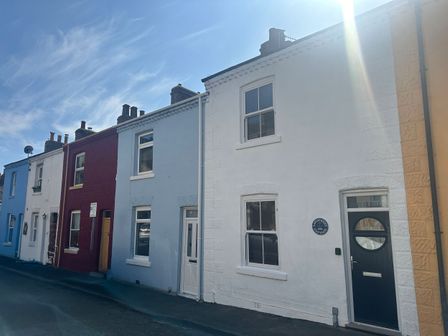A row of terraced houses with different colored facades on a street at Launchers Cottage in Scarborough