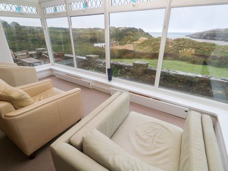 A conservatory with chairs and a view at 1 Atlantic View in Crantock