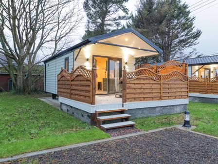 A small cabin with wooden fencing on a raised platform with steps leading to the door at MUSSENDEN CABIN Magilligan near Castlerock