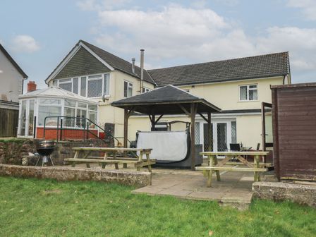 A backyard with picnic tables a barbecue a gazebo and a shed behind a two story house at Greenhaven in Narberth