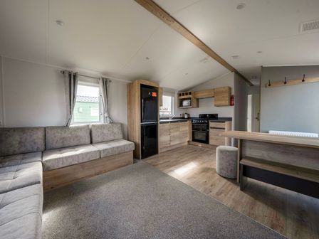 A living room with kitchen appliances and seating area at Sand and Splash - Hayling Island