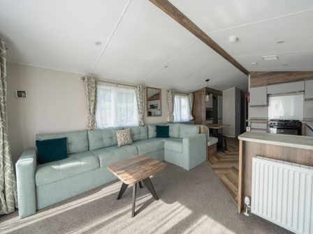 A living room with a sofa and table at Wavecrest - Hayling Island Holiday Park