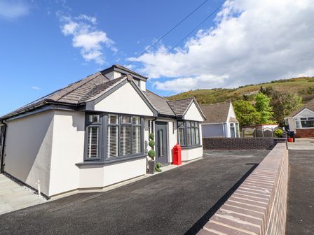 A bungalow with bay windows and a brick wall in front at Ty Blodau near Prestatyn