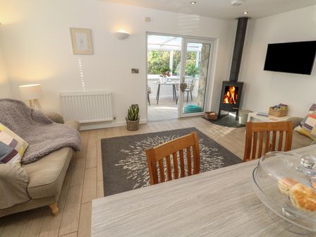 A living room with sofas a rug a wood burning stove and a table with chairs at The Duck House in Gulval near Penzance
