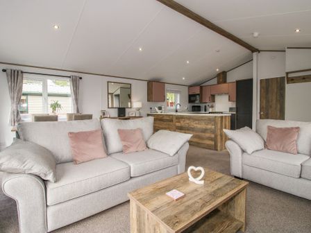 A living room with sofas and kitchen area at Peony in Eardisland