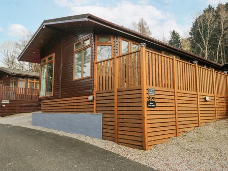 A wooden lodge with large windows and a fenced deck at Swifts Reach Lodge Kirkstone 10 Limefitt Park near Windermere