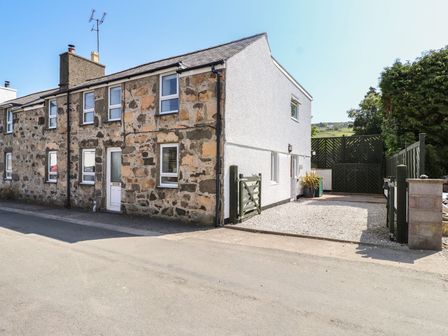 A stone and white exterior house with multiple windows and a green gate leading to a driveway at Rowarth in Nefyn