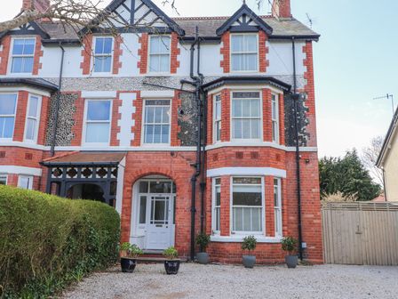 A red brick and white window house with potted plants and an arched doorway at Dolawen Bach in Conwy