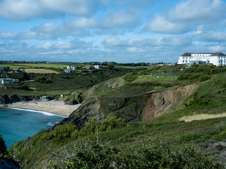 A coastal landscape with cliffs a sandy beach several houses and a large white building on a hill at Villa 2 in Mullion