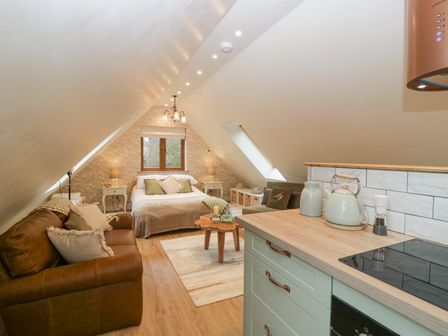 A loft bedroom with a bed sofa coffee table and kitchenette at Pheasants Rise Apartment in Ross-On-Wye