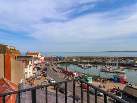 A view of a harbor with boats and cars along a street with buildings and people at Apartment 3 in Scarborough
