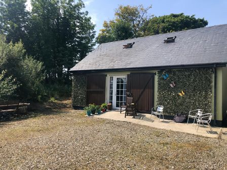 A gravel area with chairs and potted plants outside a building with shutters and skylights at River View Cottage near Muff County Donegal