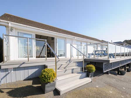 A raised deck with steps and glass railings outside a white building at Atlanta near Tintagel