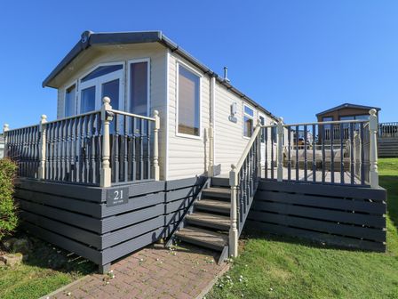 A mobile home with deck and stairs in a grassy area at 21 Bay View in Maenygroes near New Quay Ceredigion