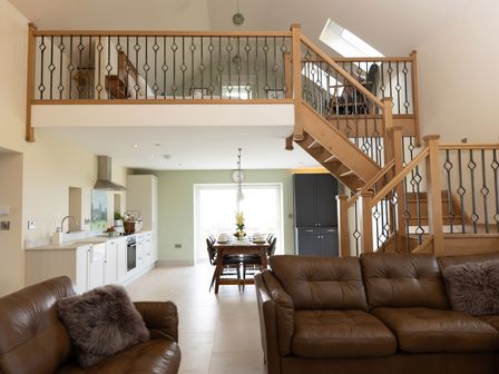 A living room with a staircase and kitchen view at Golygfa Cwrt Near Bontgoch and Penrhyncoch