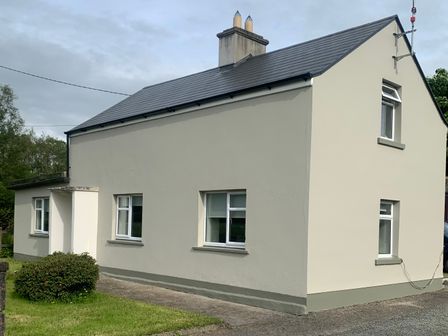 Exterior view of a two story house with multiple windows a chimney a small bush and grassy area at Kivvy Cottage Carrigallen County Leitrim