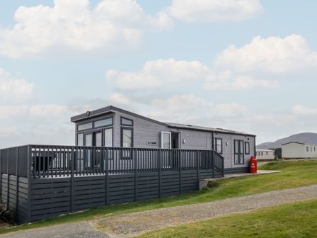 A modern static caravan with a large wooden deck on a grassy area at Amaro Mourneview in Newcastle County Down